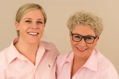 Das Team der Massagepraxis. Links Anne Spengler-Bauck, rechts Ursula Näckel-Bauck. Beide vor hellem Hintergrund, lachen in die Kamera.